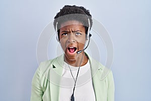 African american woman wearing call center agent headset angry and mad screaming frustrated and furious, shouting with anger