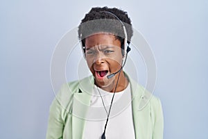 African american woman wearing call center agent headset angry and mad screaming frustrated and furious, shouting with anger