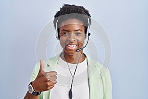 African american woman wearing call center agent headset doing happy thumbs up gesture with hand