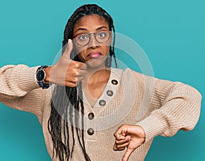 African american woman wearing casual clothes doing thumbs up and down, disagreement and agreement expression