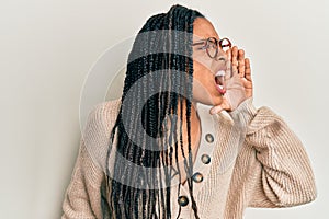 African american woman wearing casual clothes and glasses shouting and screaming loud to side with hand on mouth