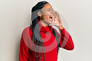African american woman wearing casual winter sweater shouting and screaming loud to side with hand on mouth