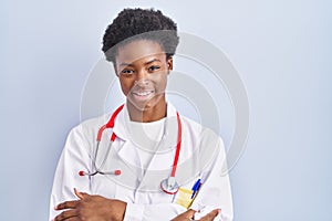 African american woman wearing doctor uniform and stethoscope happy face smiling with crossed arms looking at the camera