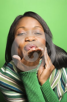 African-American woman wearing green scarf blowing kiss at viewe