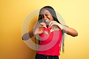 African american woman wearing red casual t-shirt standing over  yellow background smiling in love doing heart symbol