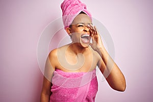 African american woman wearing shower towel after bath over pink isolated background shouting and screaming loud to side with hand