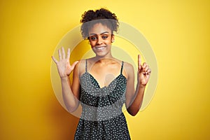 African american woman wearing summer casual green dress over isolated yellow background showing and pointing up with fingers