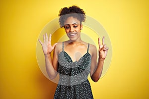 African american woman wearing summer casual green dress over isolated yellow background showing and pointing up with fingers