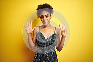 African american woman wearing summer casual green dress over isolated yellow background showing and pointing up with fingers