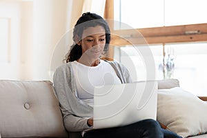 African american woman work on laptop, sit on sofa