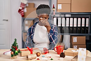 African american woman working at small business doing christmas decoration tired rubbing nose and eyes feeling fatigue and