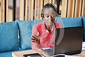 African american woman works in a call center operator and customer service agent wearing microphone headsets working on laptop