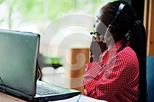 African american woman works in a call center operator and customer service agent wearing microphone headsets working on laptop