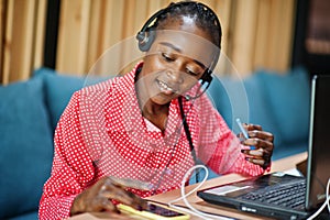 African american woman works in a call center operator and customer service agent wearing microphone headsets working on laptop