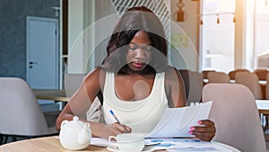 African-American woman works with diagrams at table in cafe