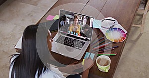 African american woman writing on memo notes while having a video call on laptop at home