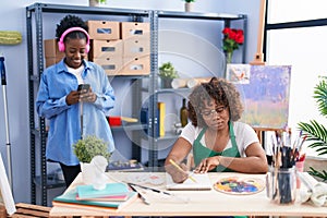 African american women artists listening to music drawing on notebook at art studio