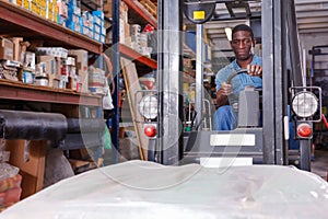 African American worker of building materials warehouse working on forklift truck