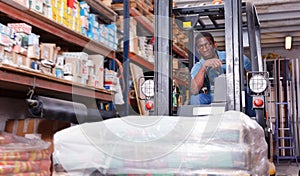 African American worker of building materials warehouse working on forklift truck