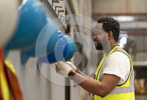 African American worker is hanging his safety helmet on the rack inside the heavy industrial factory for protection and accident