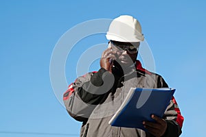 African american worker looks in work papers and talks on smartphone