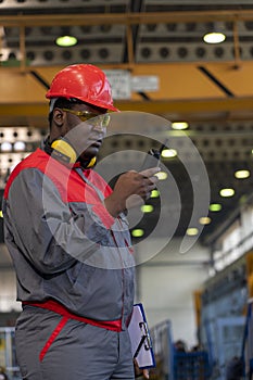 African American Worker In Protective Workwear Talking On Radio Communication Equipment In A Factory