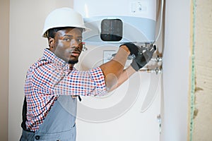 African american worker set up central gas heating boiler at home