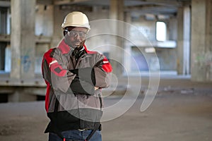 African american worker stands at construction area and looks at camera