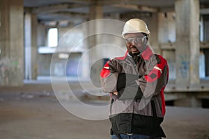 African american worker stands at construction area and looks at camera