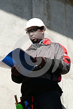 African american worker stands at construction site with work papers