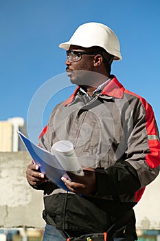 African american worker stands at construction site with work papers