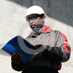 African american worker stands at construction site with work papers