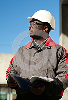 African american worker stands at construction site with work papers