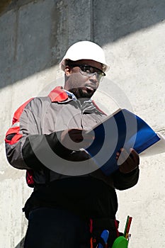 African american worker stands at construction site with work papers