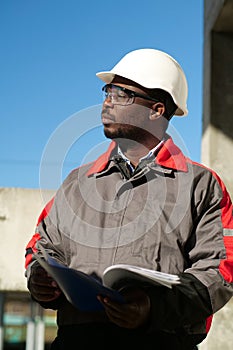 African american worker stands at construction site with work papers