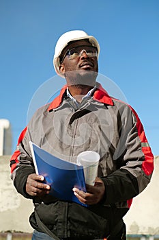 African american worker stands at construction site with work papers