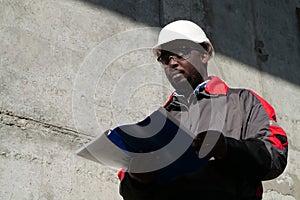 African american worker stands at construction site with work papers