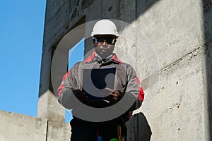 African american worker stands at construction site with work papers