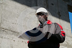 African american worker stands at construction site with work papers