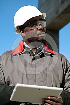 African american worker with tablet computer stands at construction site