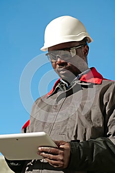 African american worker with tablet computer stands at construction site