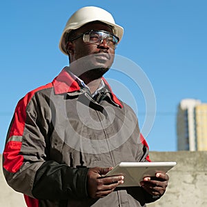 African american worker with tablet computer stands at construction site