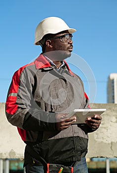 African american worker with tablet computer stands at construction site