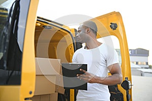 african american Worker unloading boxes from van outdoors. Moving service concept. Male employee of moving company makes