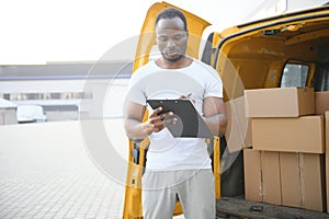 african american Worker unloading boxes from van outdoors. Moving service concept. Male employee of moving company makes