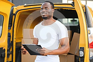 african american Worker unloading boxes from van outdoors. Moving service concept. Male employee of moving company makes