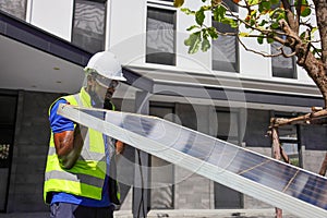 African American worker working on installing solar panel on the rooftop of the house for renewable energy and environmental