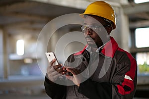 African american workman with smartphone at construction site