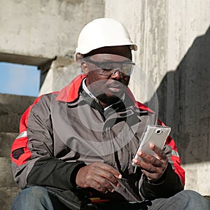 African american workman with smartphone at construction site