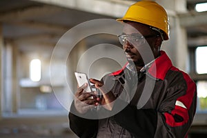 African american workman with smartphone at construction site